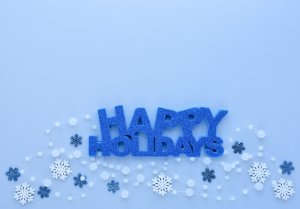 Christmas or New Year greeting card. Greeting “Happy Holidays” and snowflakes on pastel blue background. Flat lay, top view, copy space