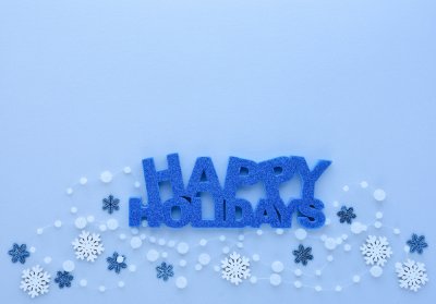 Christmas or New Year greeting card. Greeting “Happy Holidays” and snowflakes on pastel blue background. Flat lay, top view, copy space
